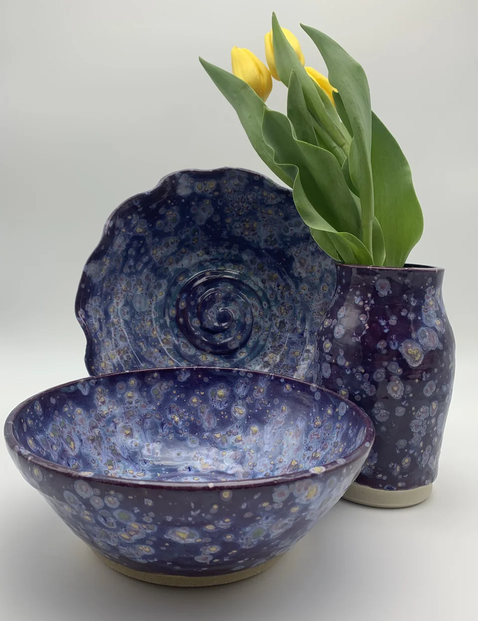 Handmade purple-glazed bowls and vase with yellow tulips